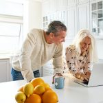 Senior couple relaxing in a kitchen with a laptop
